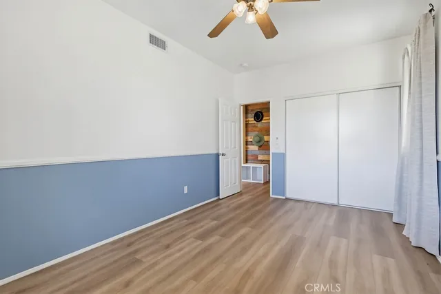 an empty room with wooden floor fan and windows