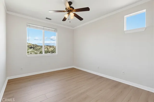 an empty room with wooden floor fan and windows