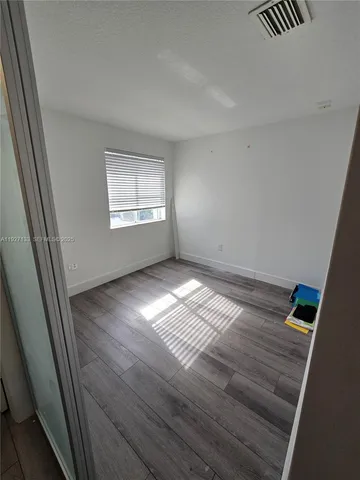 a view of empty room with wooden floor and fan