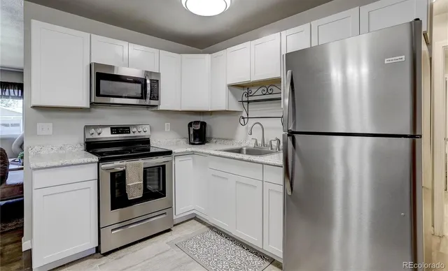 a kitchen with stainless steel appliances white cabinets white stove a microwave and a refrigerator