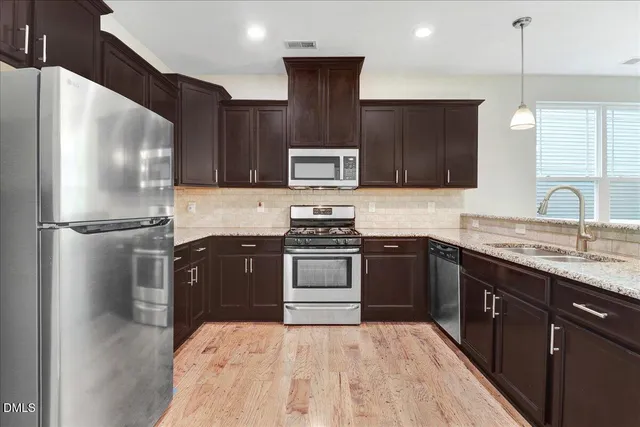 a kitchen with stainless steel appliances granite countertop a refrigerator a sink a stove a microwave and a refrigerator