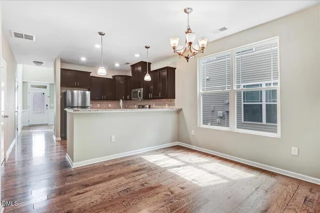 a view of an empty room with wooden floor and windows