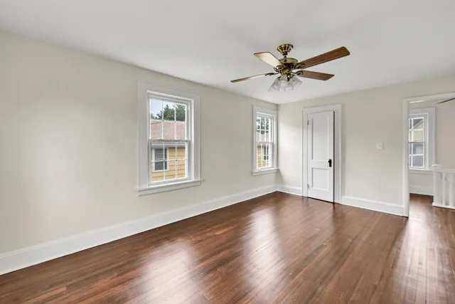 a view of a livingroom with a hardwood floor ceiling fan and windows