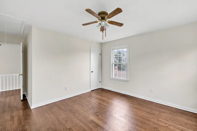an empty room with wooden floor ceiling fan and windows