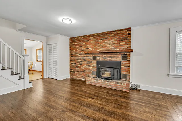 an empty room with wooden floor fireplace and windows