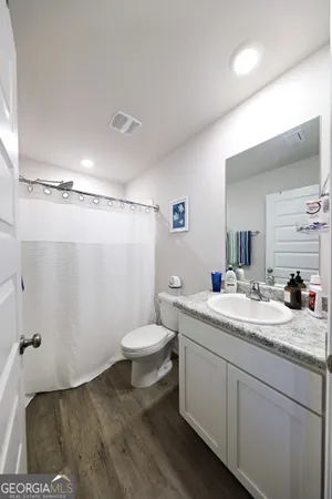 a bathroom with a granite countertop sink toilet and mirror