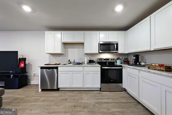 a kitchen with granite countertop a stove top oven a sink dishwasher and a microwave oven with white cabinets