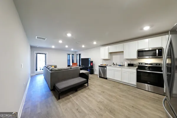 a living room with stainless steel appliances furniture and a flat screen tv
