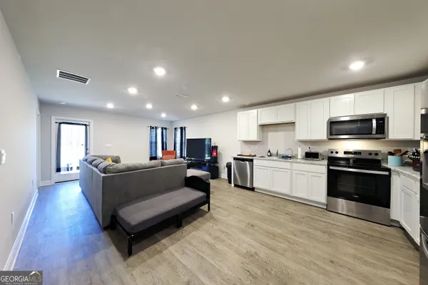 a living room with stainless steel appliances furniture and a flat screen tv