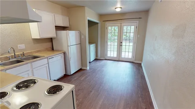 a kitchen with a refrigerator a stove a sink and a wooden floor