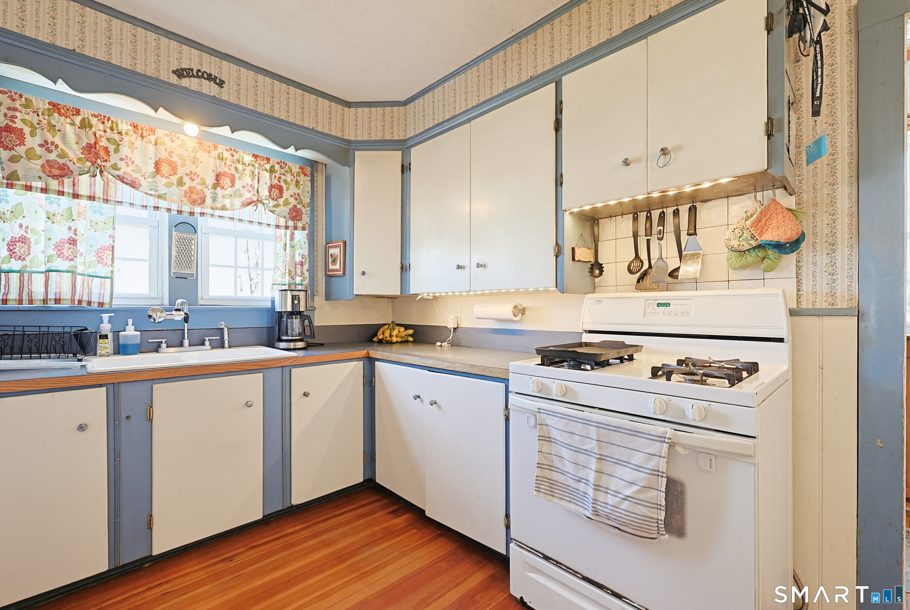 19 Church Street Plainfield, CT 06374 - Photo 11 of 39 a kitchen with a stove a sink and white cabinets with wooden floor next to windows