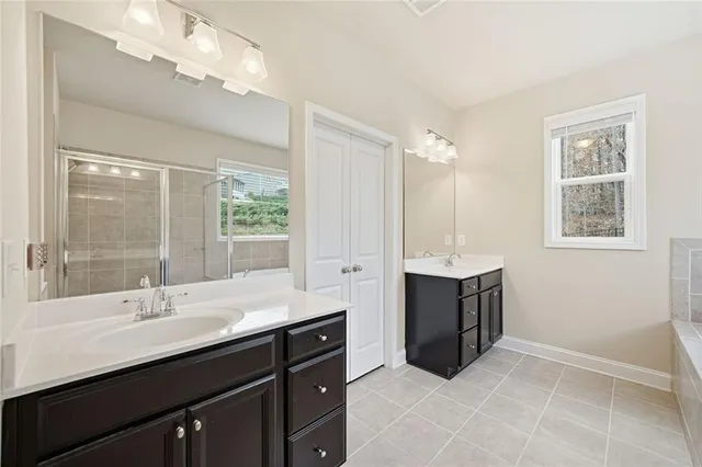 a spacious bathroom with a double vanity sink a mirror and a bathtub