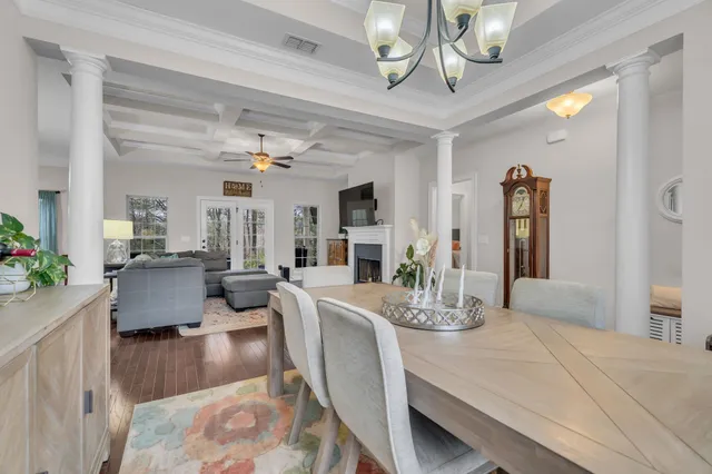 a dining room with wooden floor a chandelier a wooden table and chairs