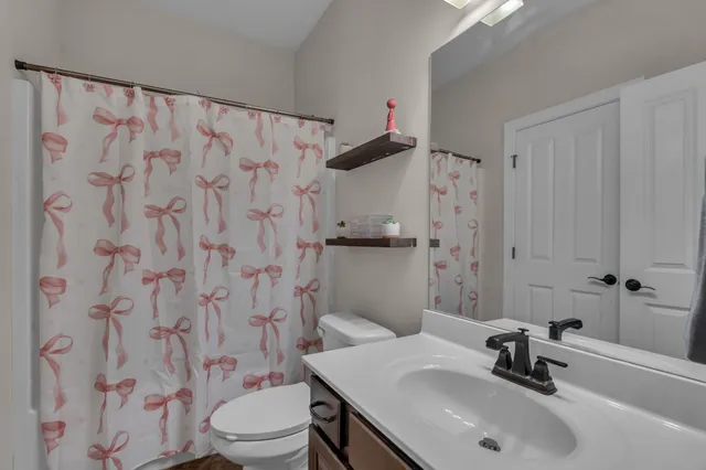 a bathroom with a sink a toilet and shower curtain