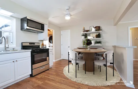 a kitchen with stainless steel appliances kitchen island granite countertop a table chairs sink and cabinets