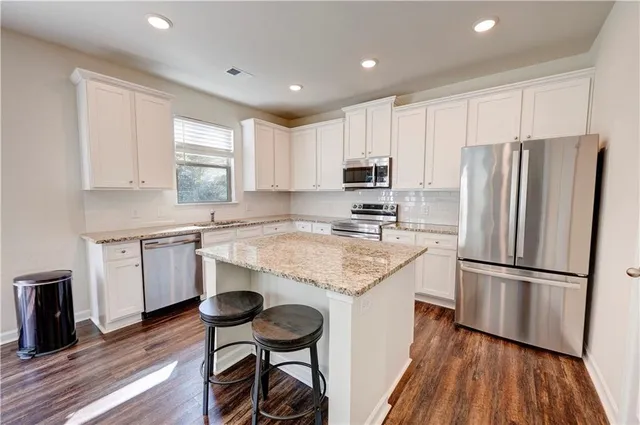 a kitchen with kitchen island granite countertop white cabinets and stainless steel appliances