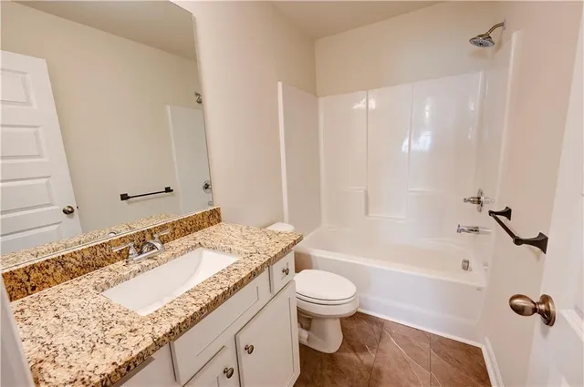 a bathroom with a granite countertop sink a toilet and bathtub