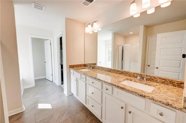 a spacious bathroom with a granite countertop sink a mirror and a shower