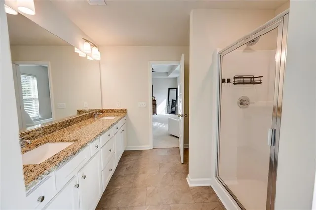 a bathroom with a granite countertop sink a mirror and a shower
