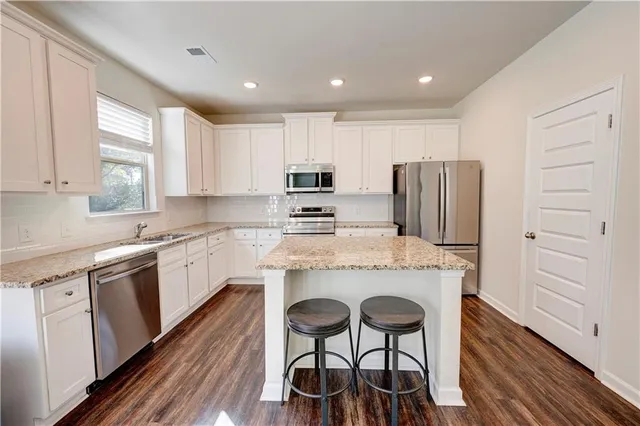 a kitchen with a refrigerator a stove cabinets and wooden floor