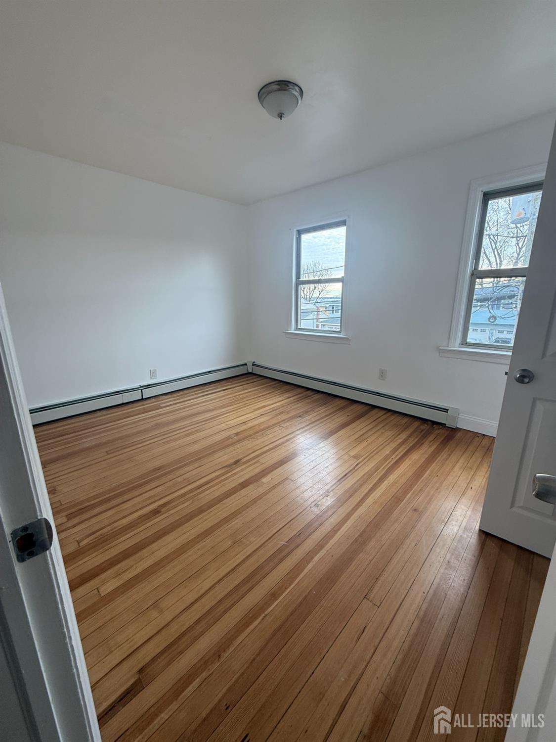 579 Florida Grove Road Perth Amboy, NJ 08861 - Photo 3 of 14 an empty room with wooden floor and windows