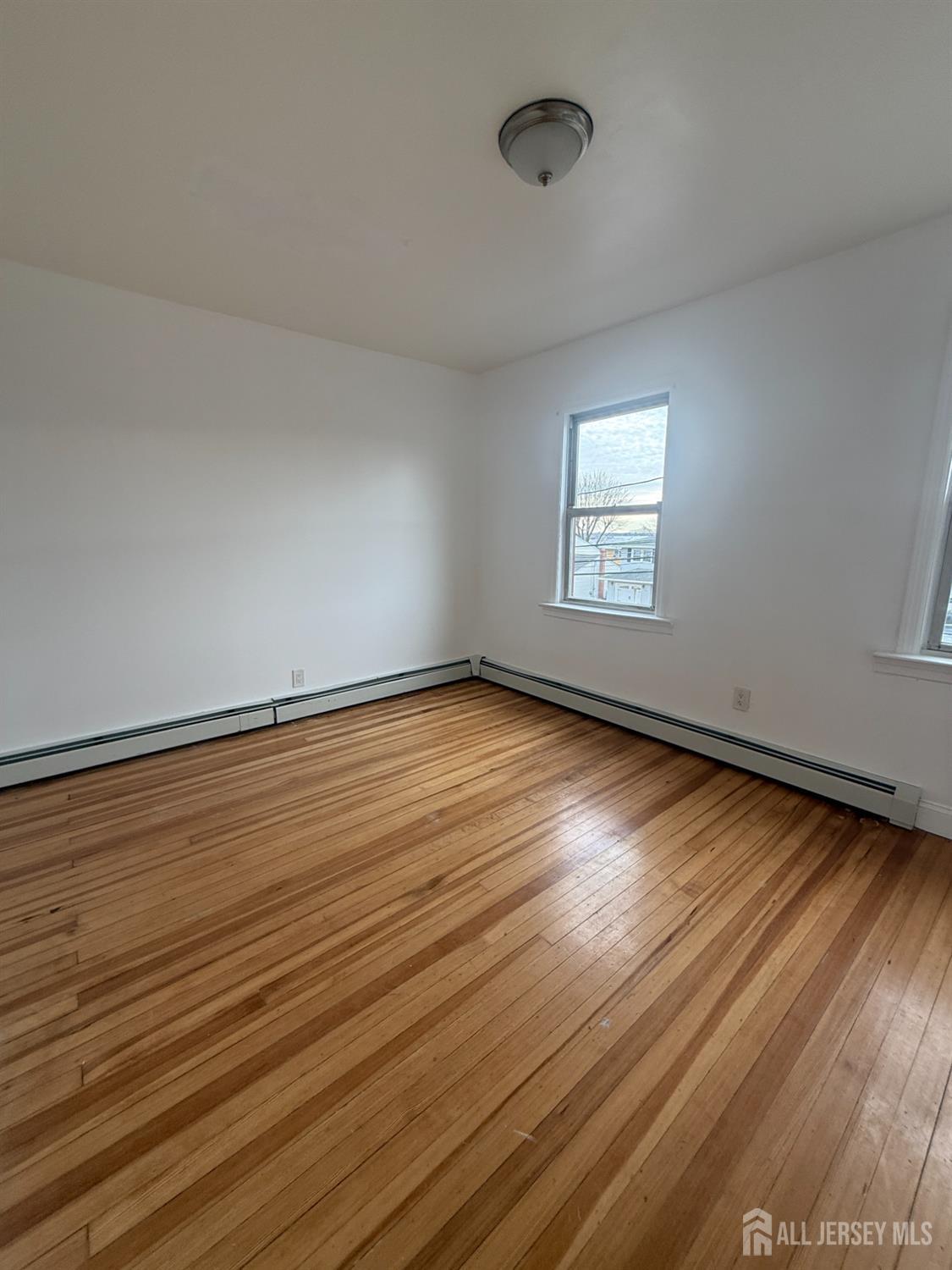 579 Florida Grove Road Perth Amboy, NJ 08861 - Photo 4 of 14 an empty room with wooden floor and windows