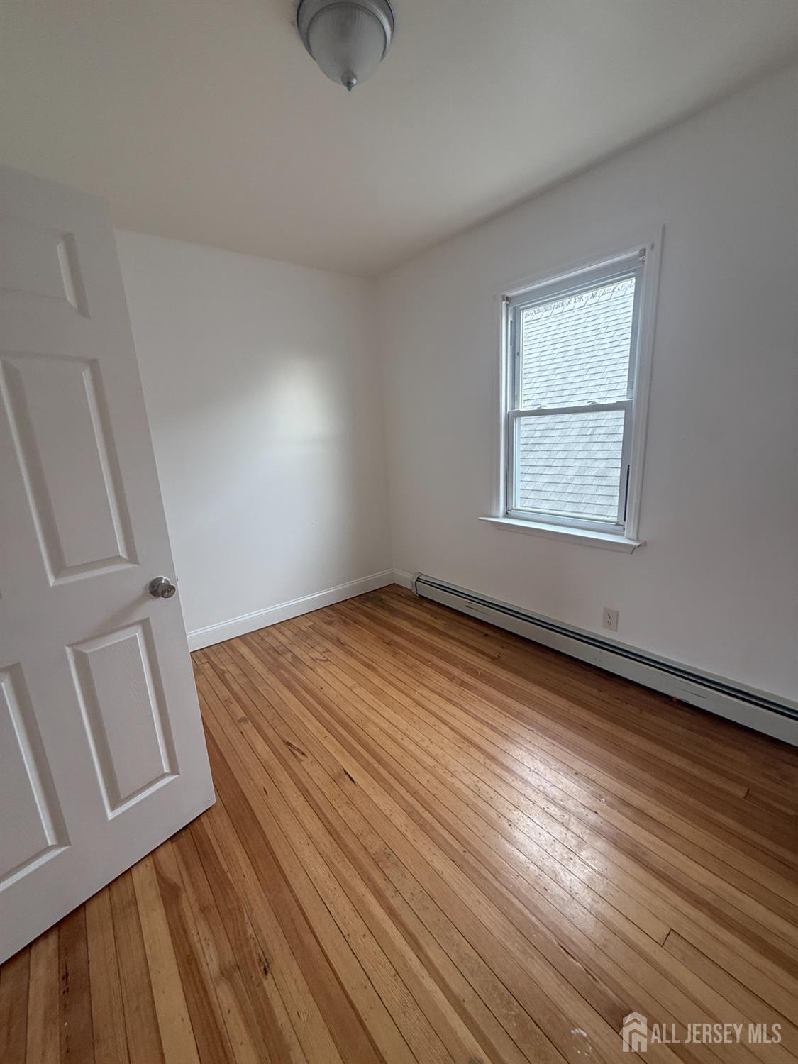 579 Florida Grove Road Perth Amboy, NJ 08861 - Photo 6 of 14 an empty room with wooden floor and windows