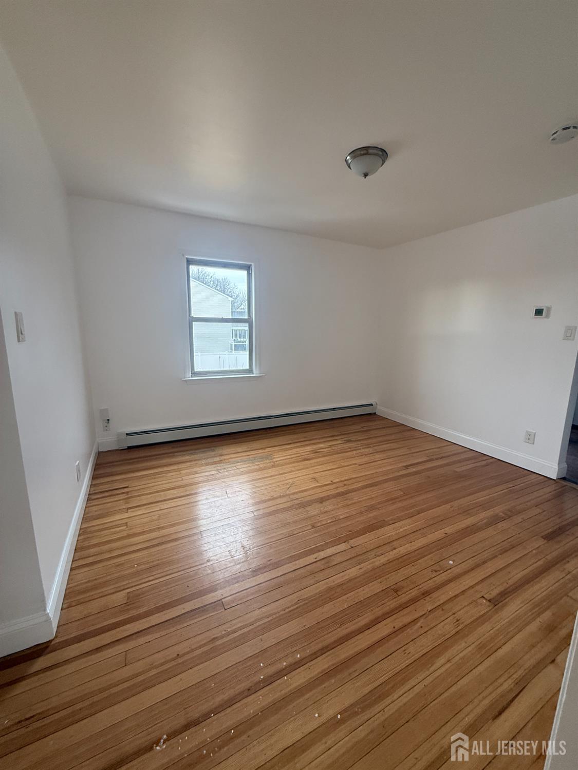 579 Florida Grove Road Perth Amboy, NJ 08861 - Photo 8 of 14 an empty room with wooden floor and windows