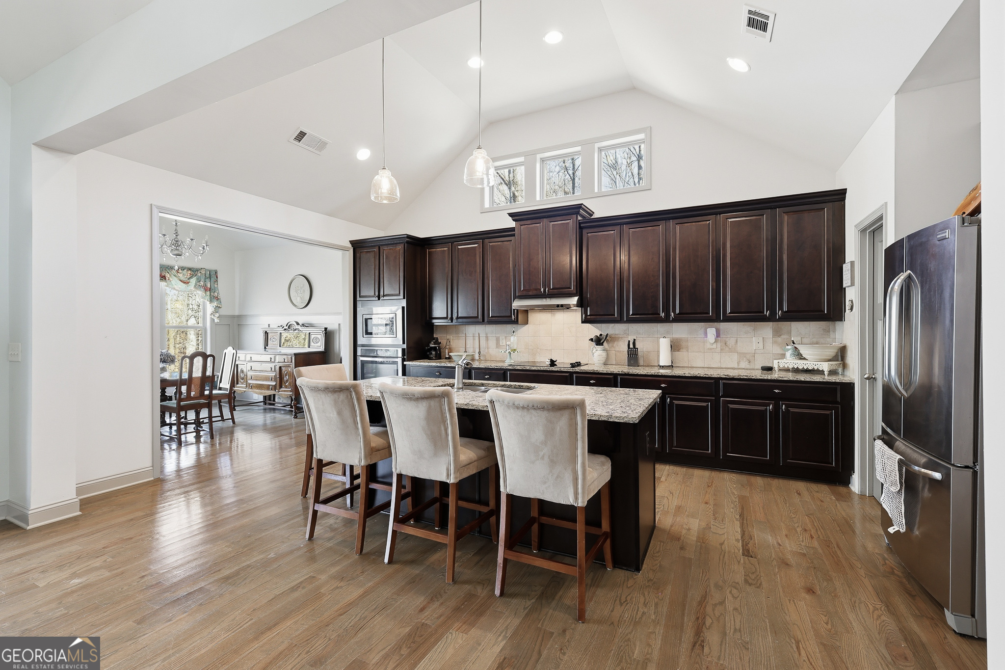 56 Creek Side Court Jefferson, GA 30549 - Photo 16 of 46 a kitchen with stainless steel appliances kitchen island granite countertop a refrigerator a stove a sink a dining table and chairs with wooden floor