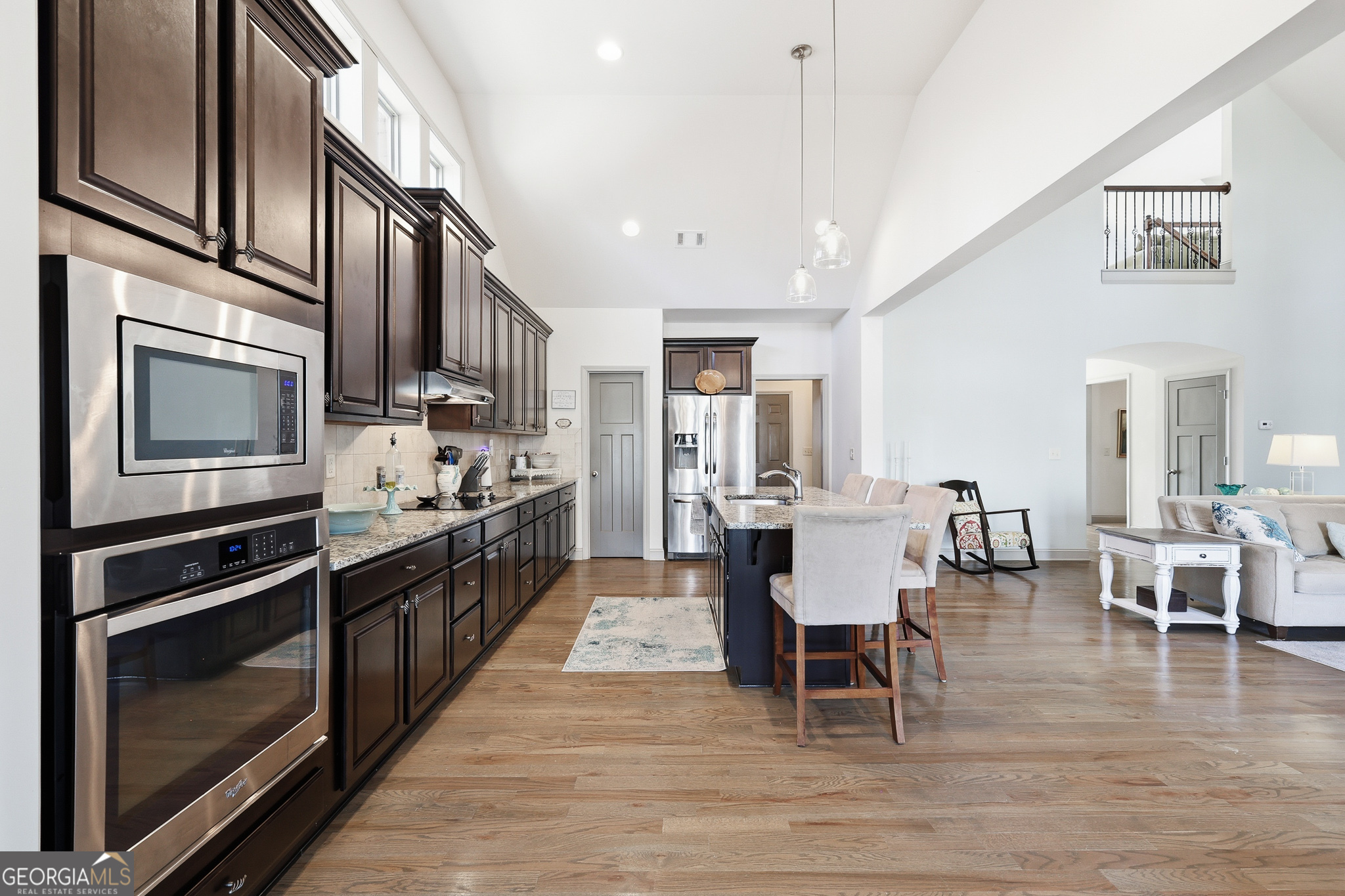 56 Creek Side Court Jefferson, GA 30549 - Photo 17 of 46 a large kitchen with stainless steel appliances kitchen island granite countertop a large dining table and chairs with wooden floor