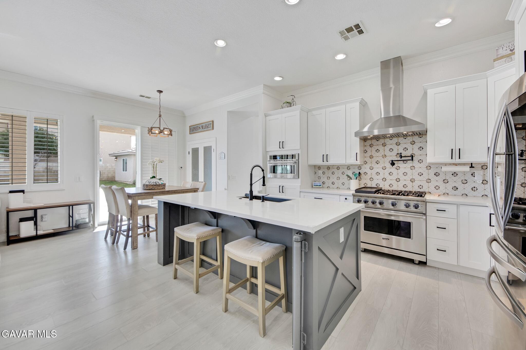 41632 Firenze Street Lancaster, CA 93536 - Photo 15 of 67 a kitchen with kitchen island a stove a table and chairs in it