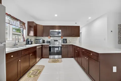 a kitchen with stainless steel appliances granite countertop a refrigerator a sink a stove a microwave and wooden cabinets