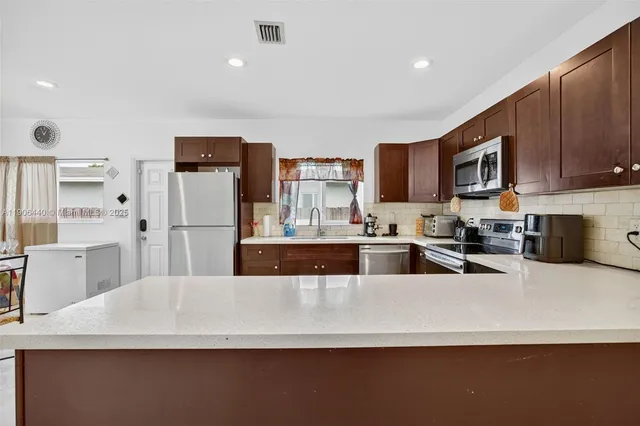 a kitchen with stainless steel appliances a refrigerator sink stove microwave and cabinets