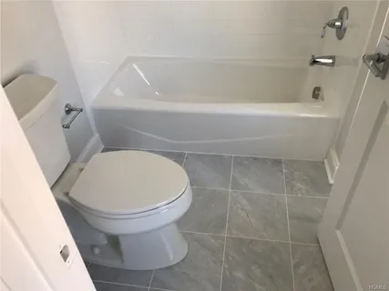 a white toilet sitting next to a bath tub