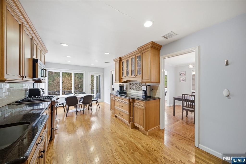 126 Sussex Road Tenafly, NJ 07670 - Photo 10 of 50 a kitchen with granite countertop a stove top oven a sink a dining table and chairs