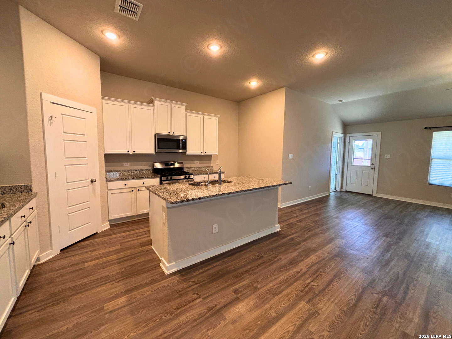 10754 Francisco Way Converse, TX 78109 - Photo 11 of 18 a kitchen with granite countertop a stove top oven a sink and white cabinets with wooden floor