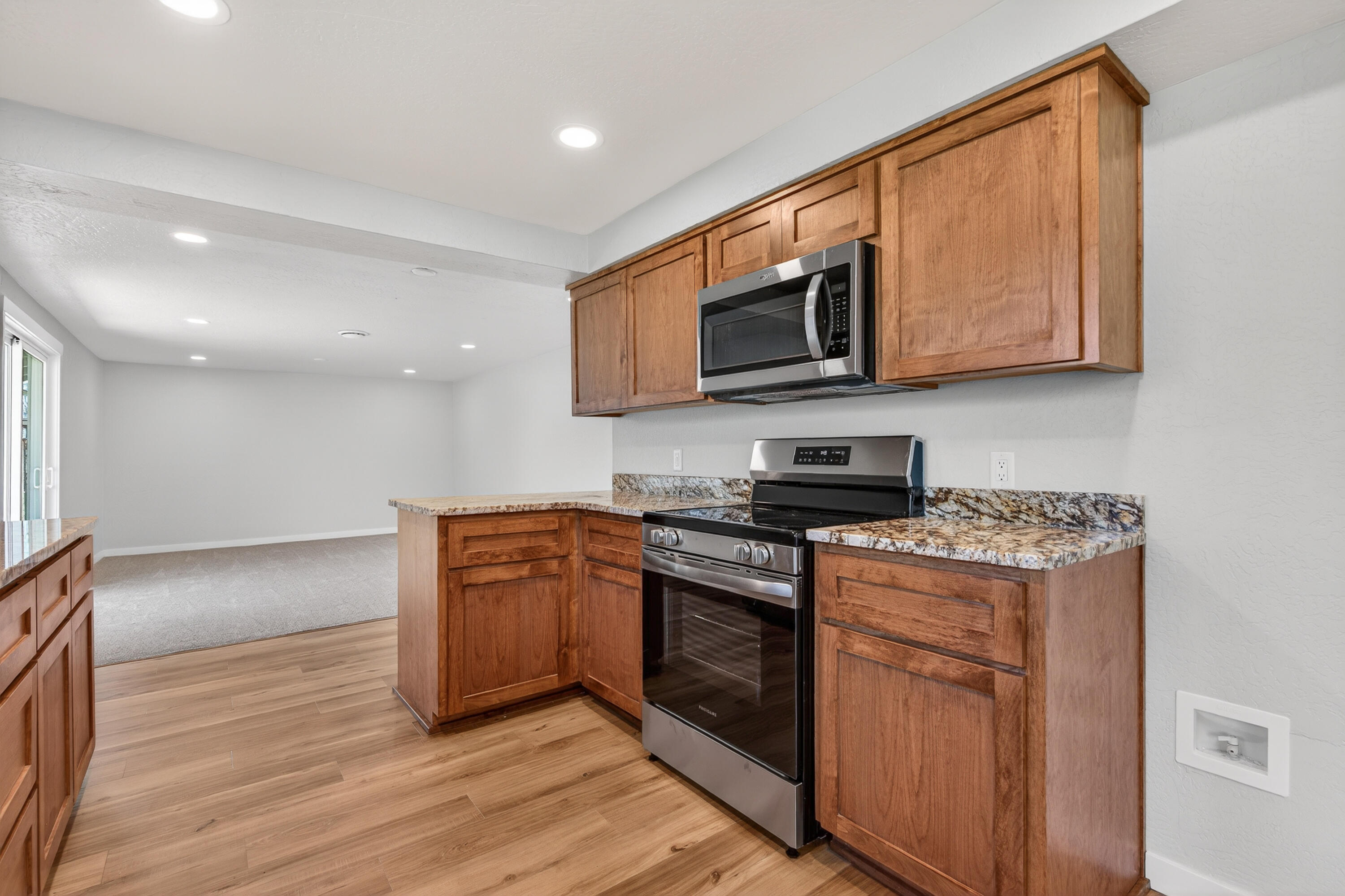 550 Experiment Station Road Medford, OR 97501 - Photo 9 of 27 a kitchen with stainless steel appliances granite countertop a stove top oven a sink dishwasher and a microwave oven with wooden floor