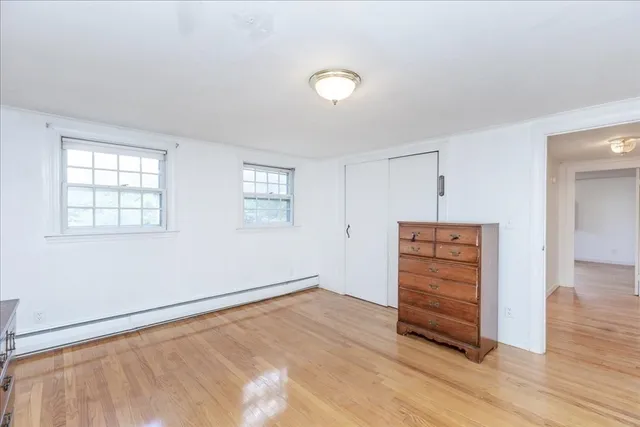an empty room with wooden floor closet and windows