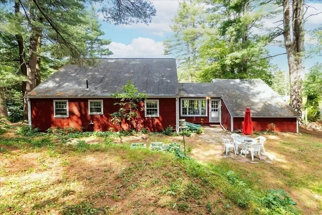 a view of a brick house with many windows plants and large tree