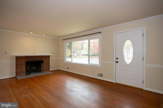 an empty room with wooden floor fireplace and windows