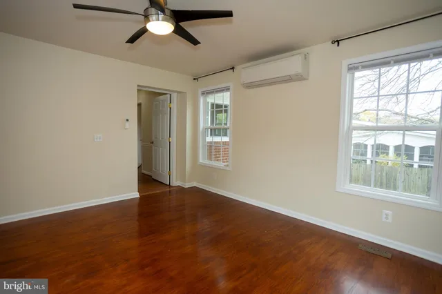 a view of an empty room with wooden floor fireplace and a window