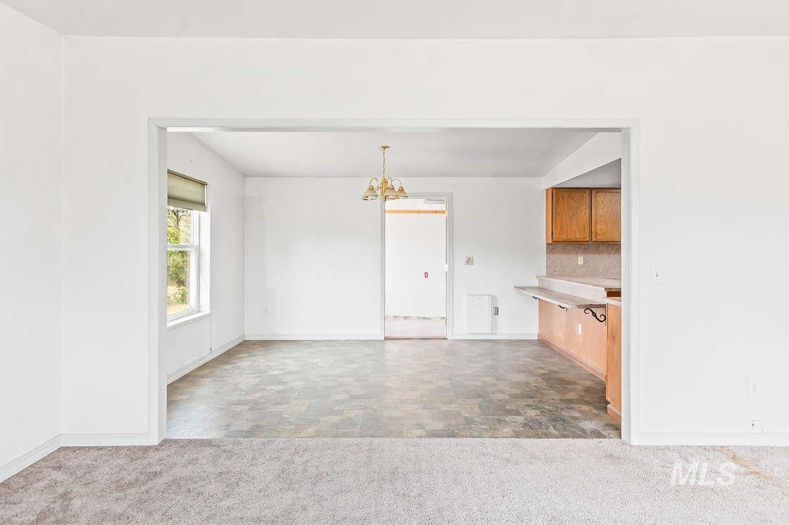 255 3 Bear Creek Road Kendrick, ID 83537 - Photo 14 of 44 Kitchen with a chandelier, carpet, light countertops, stone finish floors, and backsplash