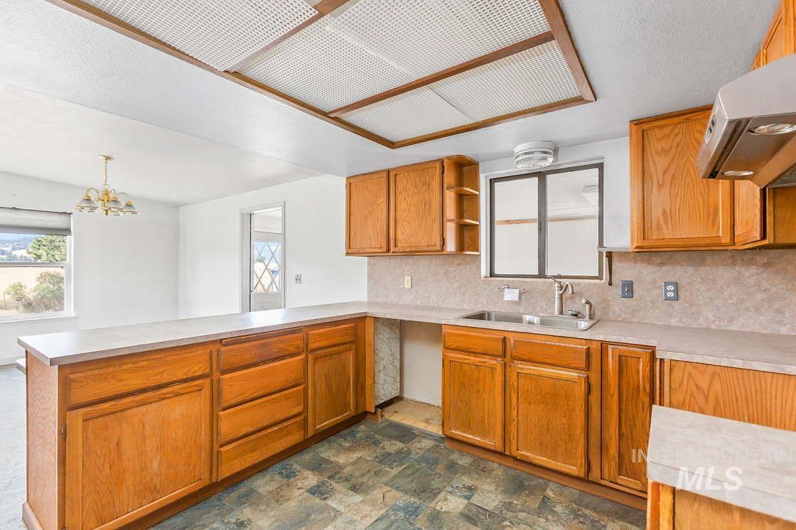 255 3 Bear Creek Road Kendrick, ID 83537 - Photo 17 of 44 Kitchen featuring a peninsula, decorative backsplash, light countertops, open shelves, and stone finish flooring