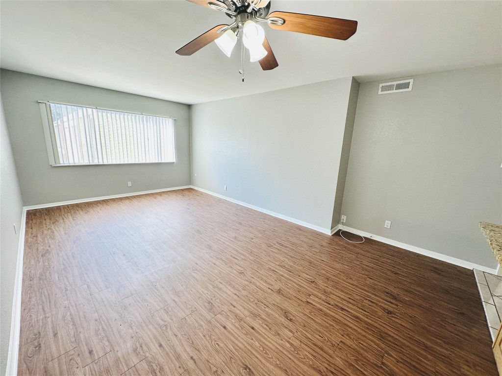 601 West 11th Street, Unit 223 Austin, TX 78701 - Photo 4 of 10 an empty room with wooden floor chandelier fan and windows