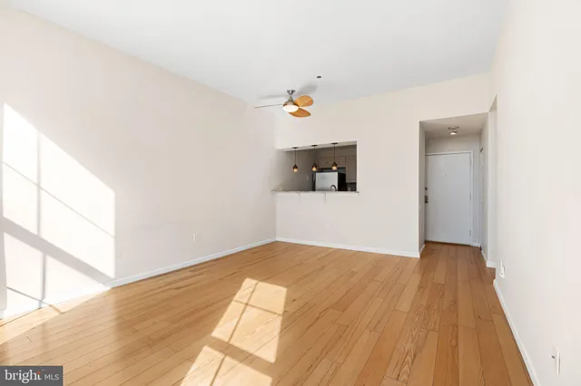 a view of empty room with wooden floor and fan