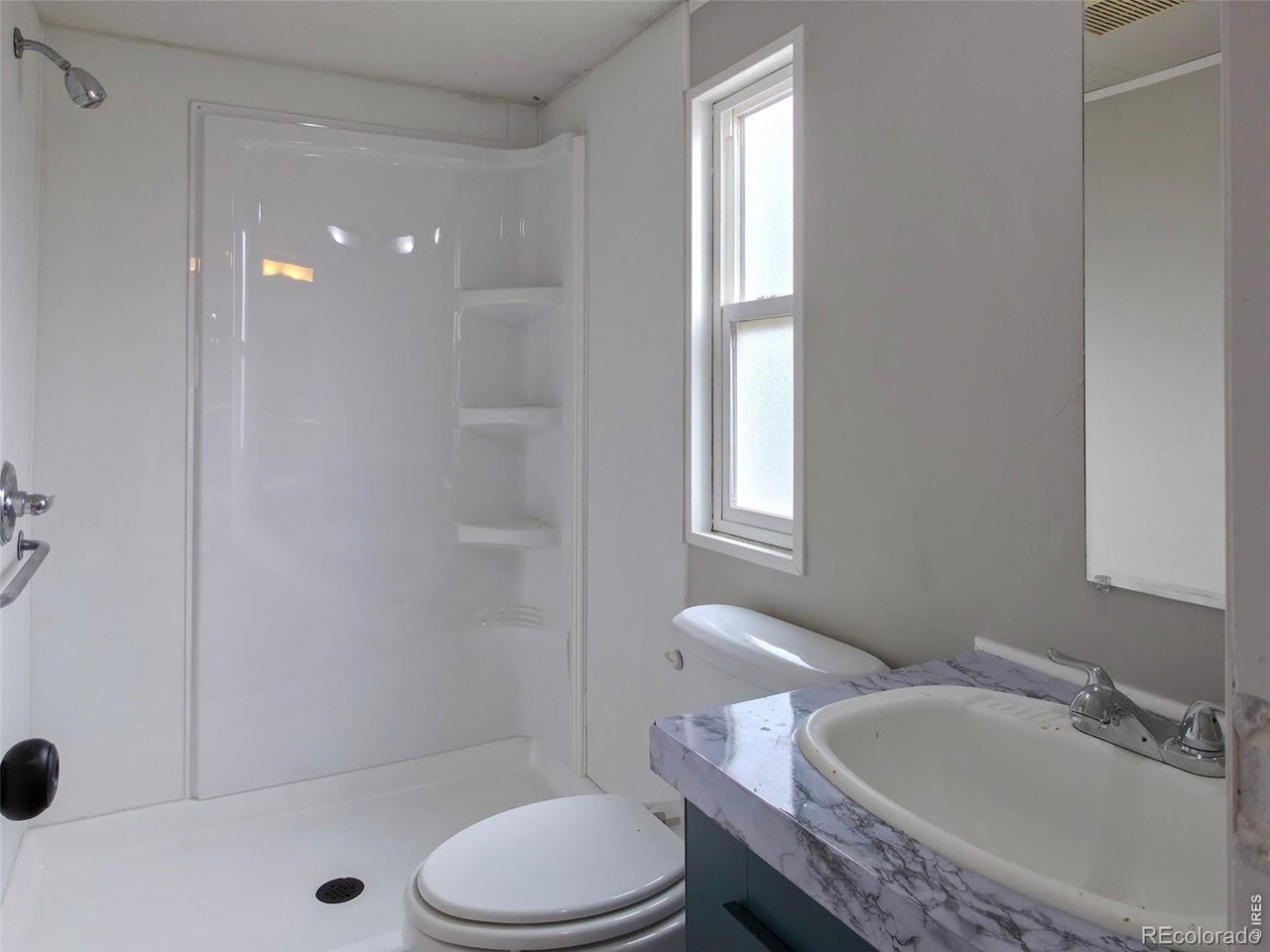 1401 9th Street, Unit 80 Fort Lupton, CO 80621 - Photo 19 of 21 a bathroom with a granite countertop sink toilet a mirror and shower