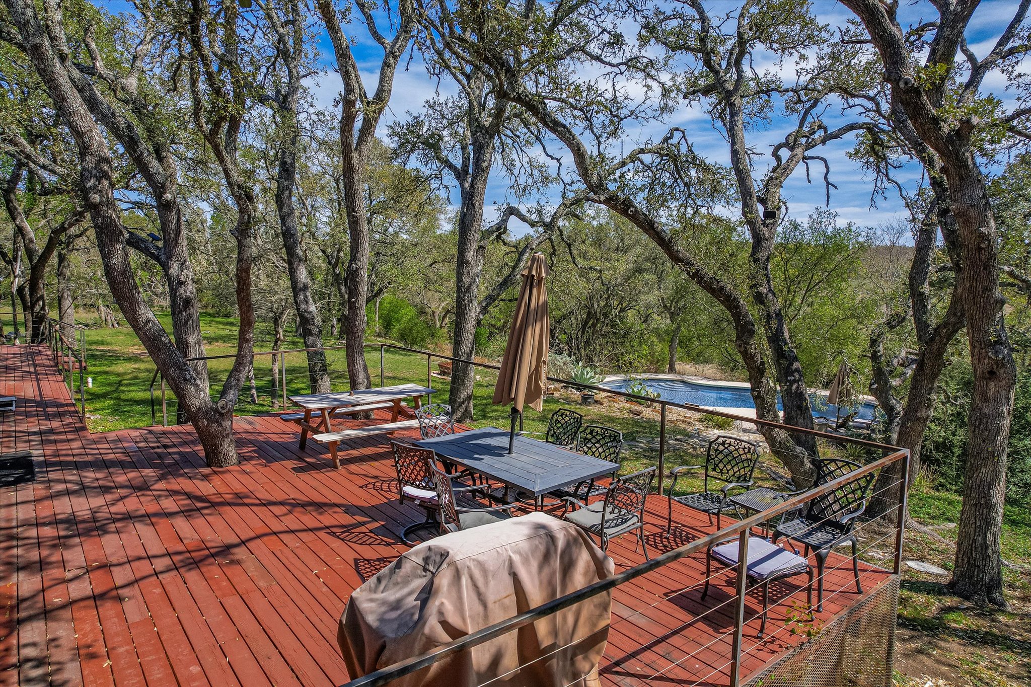 411 Whitetail Ridge Austin, TX 78737 - Photo 29 of 38 Deck featuring outdoor dining area, a grill, view of scattered trees, and a pool