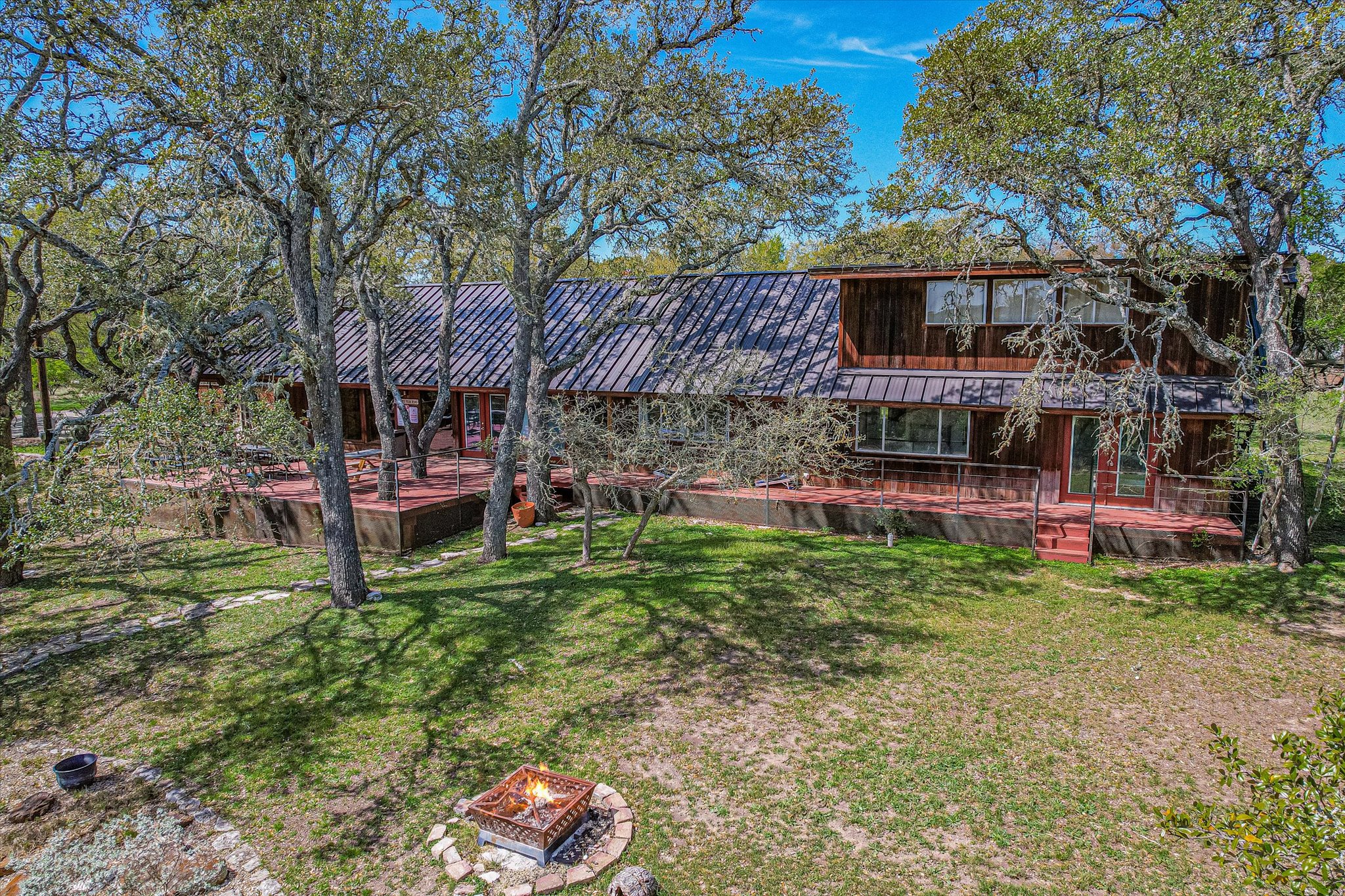 411 Whitetail Ridge Austin, TX 78737 - Photo 33 of 38 Rear view of house featuring a yard, an outdoor fire pit, and a metal roof