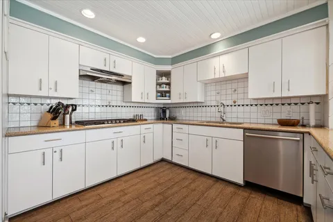 a kitchen with stainless steel appliances granite countertop white cabinets a sink and dishwasher with wooden floor