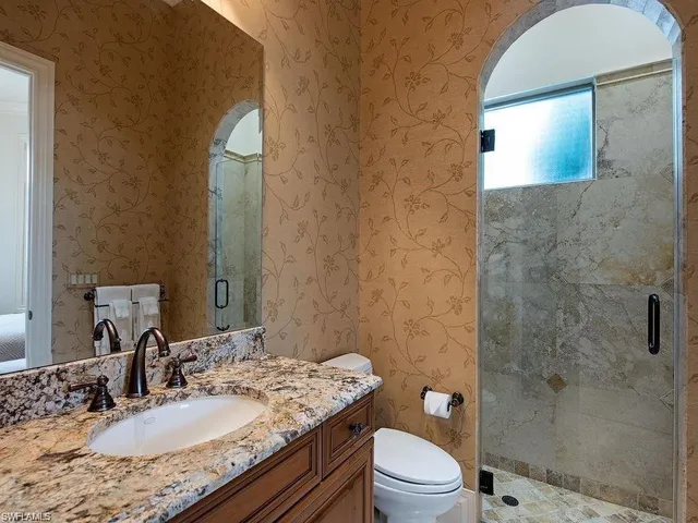 a bathroom with a granite countertop sink toilet a mirror and shower